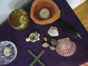 small table with purple cloth, candle, cross, shells, feather, for Lent