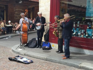 Musicians playing bass, banjo, sax, and trombone on Rue Mouffetard, Paris