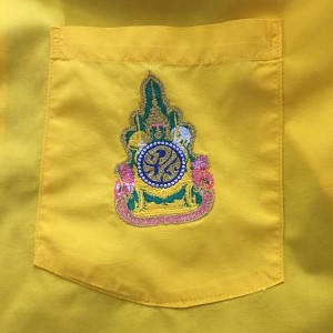 Close up photo of a the King of Thailand's crest on a yellow "king shirt."