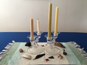 Advent wreath with taper and glass candelabra surroounded by shells, arrowhead, driftwood, and a feather.