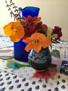 Bouquet of bright flowers and cobalt blue glass water jug on table