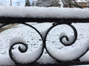 snow on top of black iron railing
