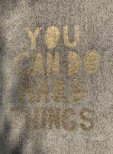 Words stenciled on sidewalk, "You Can Do Hard Things"